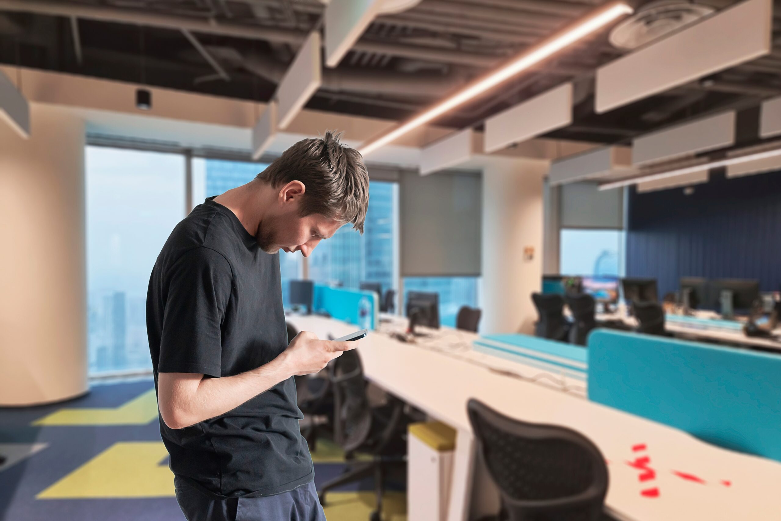 Man kijkt gebogen op zijn telefoon in een kantoor
